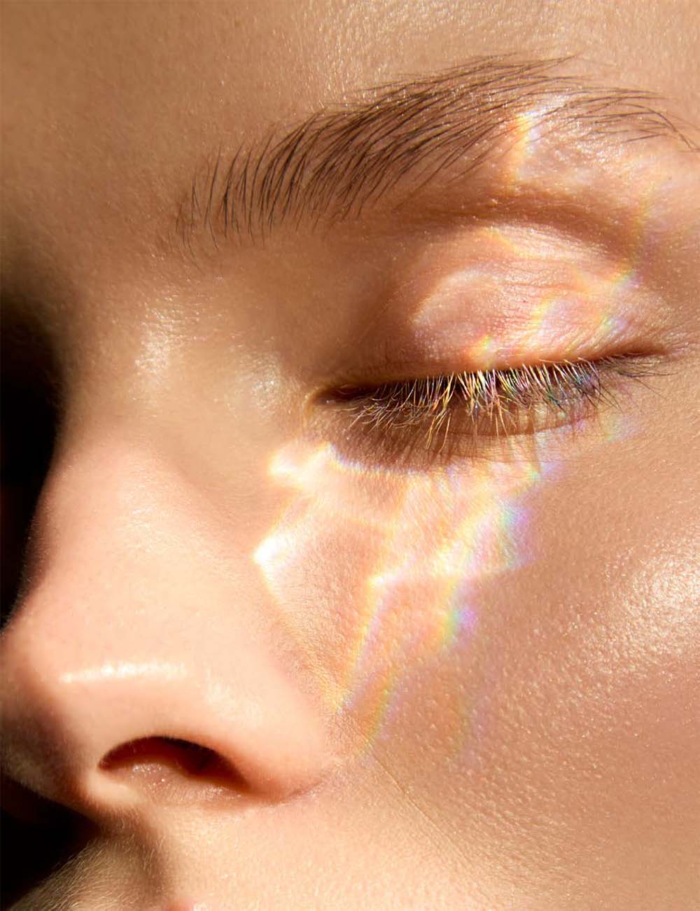 Close-up of a person's eye with a rainbow effect on the skin